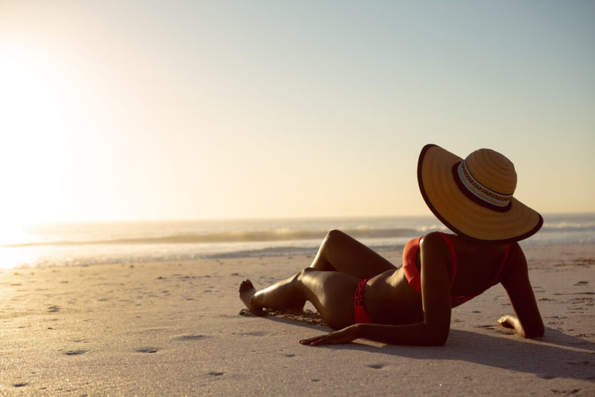 Rear view of woman in hat relaxing on the beach